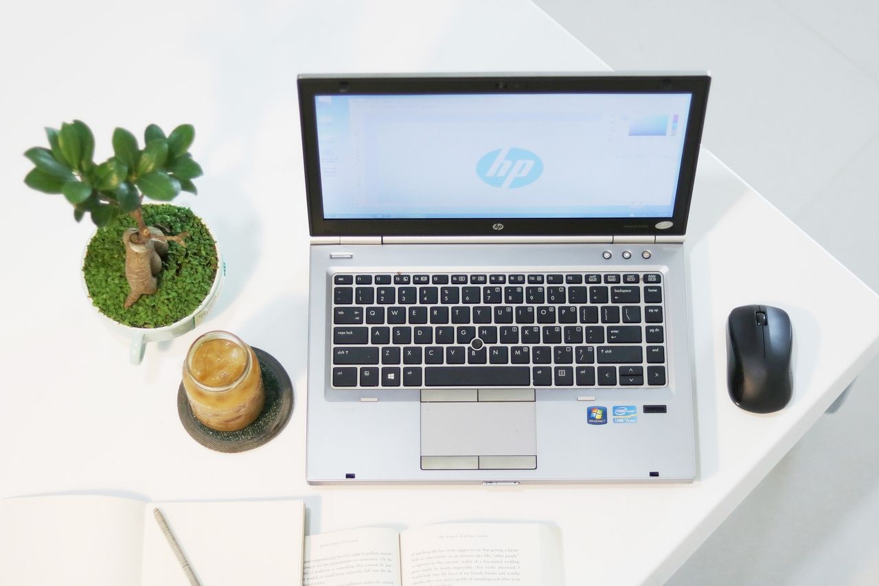 About Aerial view of a modern workspace featuring a laptop, plant, and iced coffee in a minimalist setting.