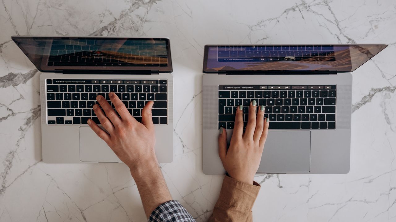 The Art of Drawing Readers In: Your attractive post title goes here Top view of hands typing on two laptops, showcasing collaboration and technology.